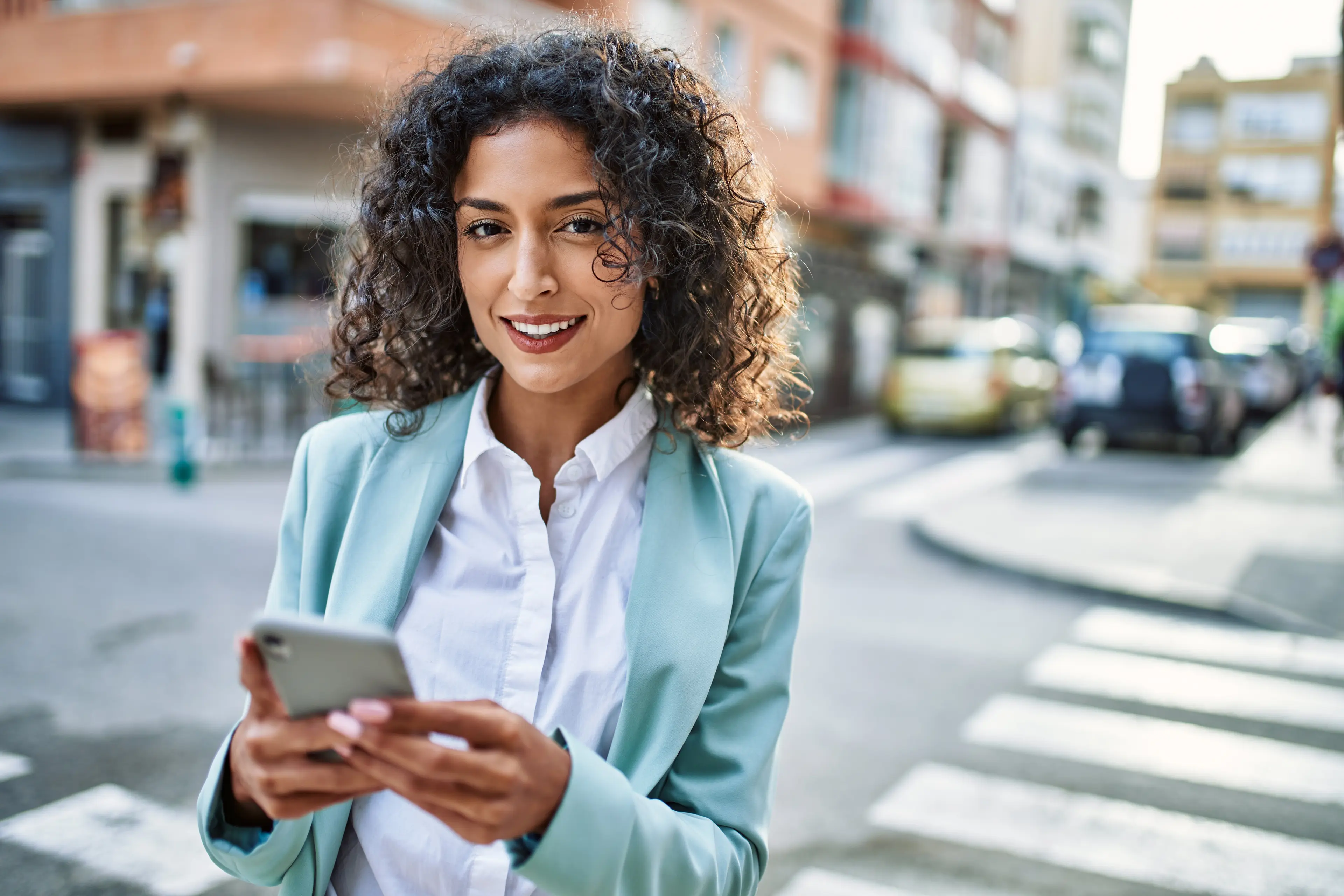 smiling person looking away from their phone at the camera